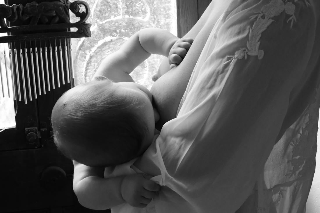 Baby nourished in his mother’s arms, the tenderness of breastfeeding in black and white