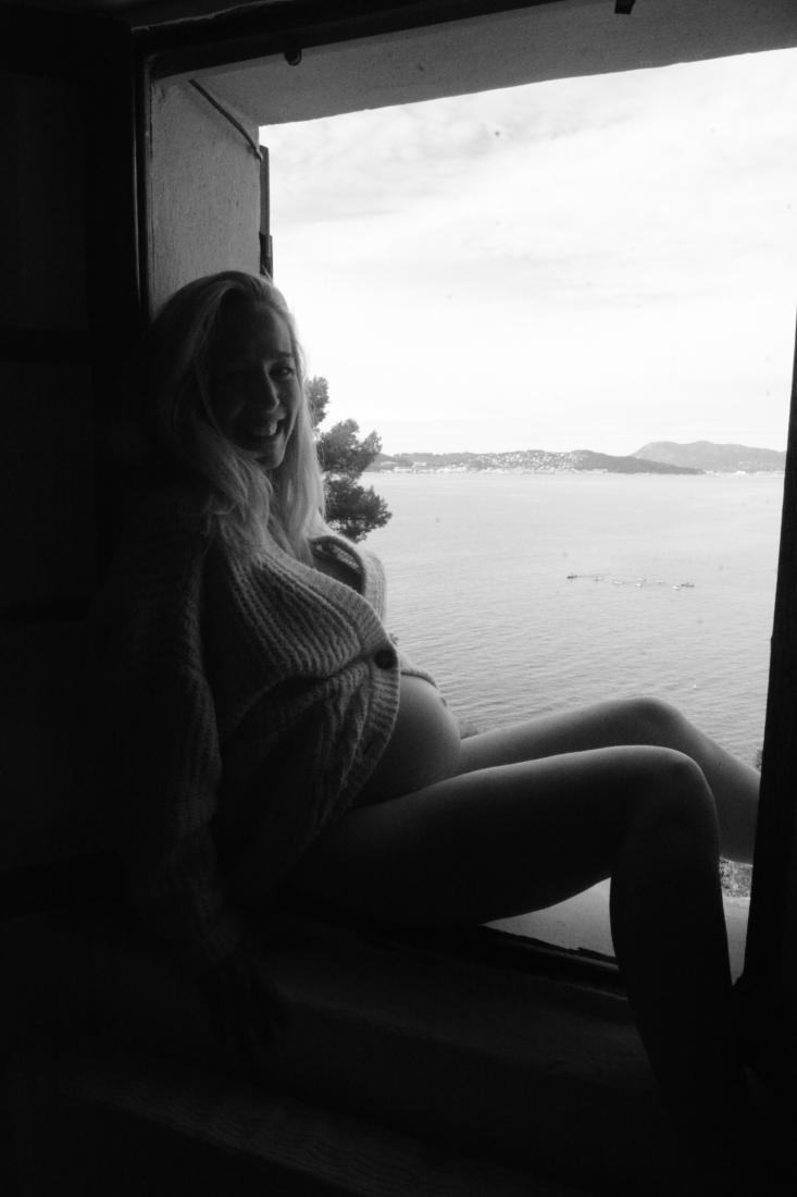 Expectant mother at the window of a family home overlooking the bay of Toulon, pregnancy