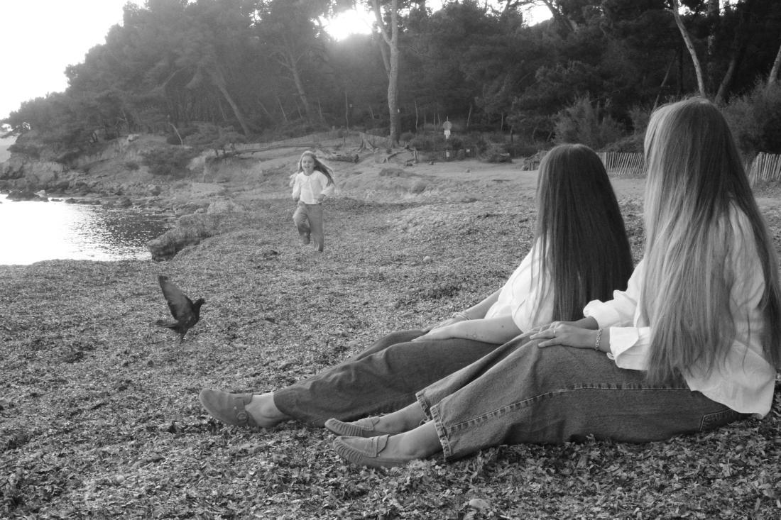 Famille au bord de la mer, deux sœurs et leur maman tournées vers le nouveau-né