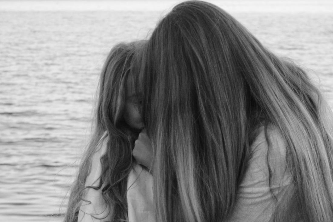 Mère et fille au bord de la mer, chevelures mêlées sur l’horizon marin, noir et blanc