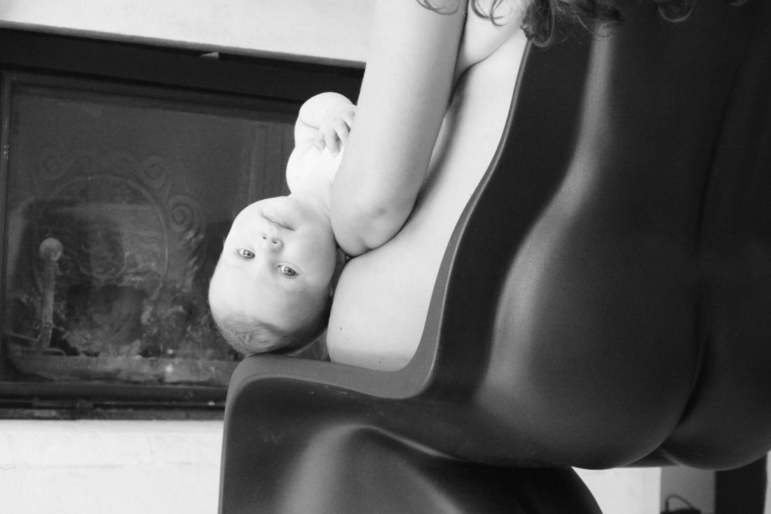Portrait of a newborn with a deep gaze in his mother’s arms, black and white