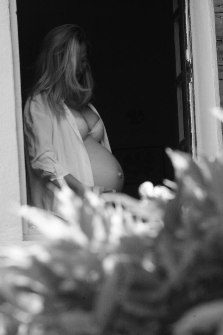 Future maman contemplant son ventre dans une maison de famille baignée de lumière
